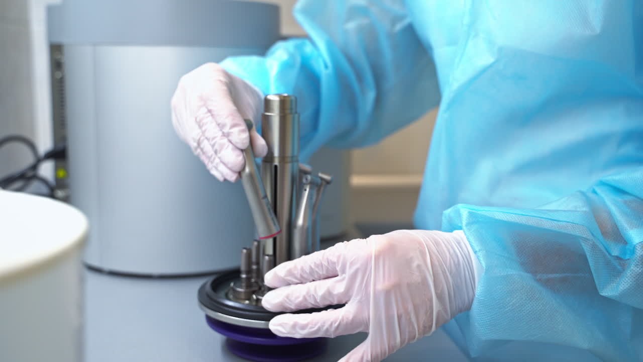 Gloved hands put the nozzles from dental machine into a special holder. Keeping and management of dental care instruments. Close up.