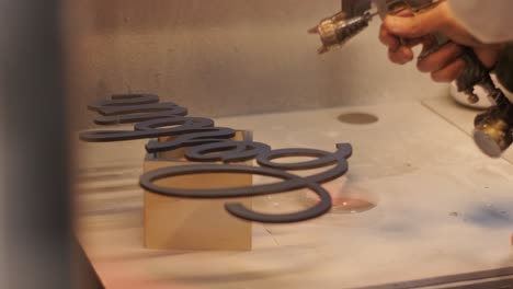 a worker hands paints a wooden product with a gun. painting of plywood products made on a cnc laser machine