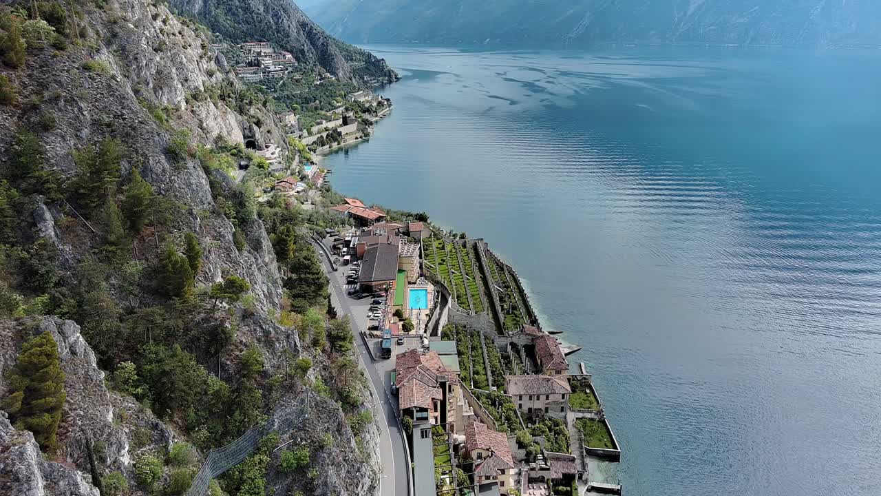 Drone video captures breathtaking aerial view of Lake Como's rugged terrain. Stunning landscape with winding roads, hills, and natural beauty under clear skies. No people visible