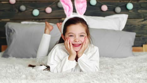 smiling girl with bunny ears lying on the bed