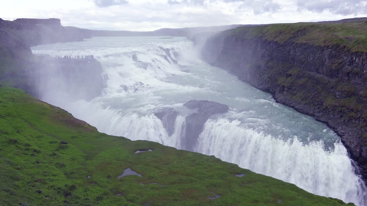 la espectacular y masiva cascada gullfoss fluye en islandia con turistas en el acantilado en la distancia 1