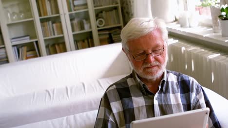 senior man using digital tablet in living room