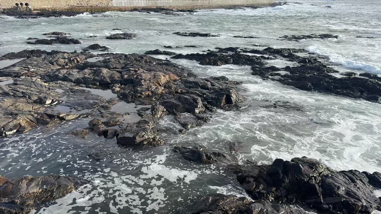 Waves crash on Rocks near Cape Town’s lighthouse on Mouille Point