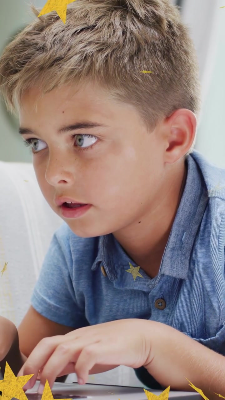 Video verticale: Ragazzo che digita su un tablet e fa apparire stelle gialle fluttuanti sopra le mani in un'app di apprendimento.
