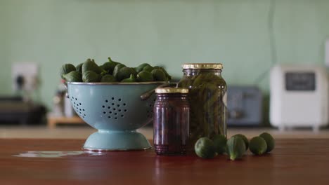 Close-up-of-countertop-in-kitchen-with-vegetables-and-jars