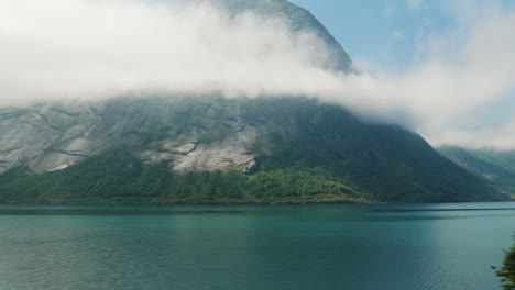 the shore of the fjord the top of the mountains are drowning in the clouds view from the window of t