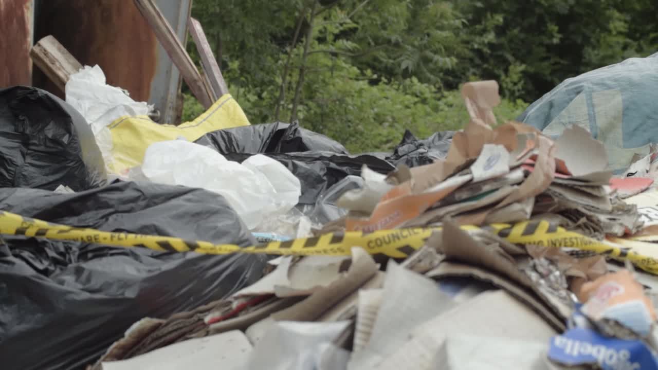 Illegal waste and garbage dumped in countryside wide tilting shot
