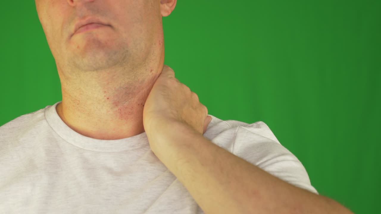 Uomo che si strofina collo e spalle con la mano sinistra. Primo piano estremo frontale. Inquadratura fissa.