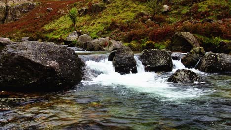 Un-Arroyo-Cristalino-Que-Cae-En-Cascada-A-Través-De-Un-Exuberante-Valle-En-Snowdonia,-Gales-Del-Norte