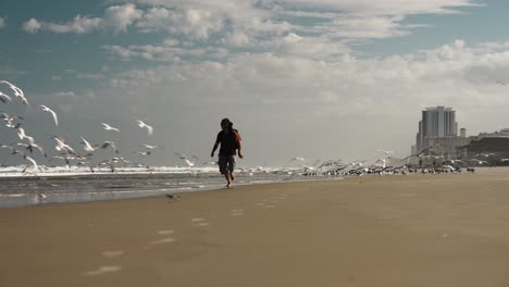 Escena-épica-Del-Hombre-Corriendo-En-La-Playa-Con-Miles-De-Gaviotas-Volando