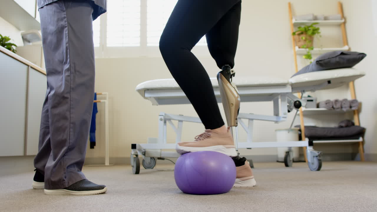 Balancing on exercise ball, person with prosthetic leg receiving physical therapy