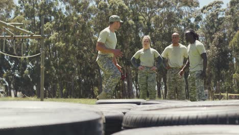 Diverse-group-of-soldiers-listening-to-male-instructor-explain-exercise-on-army-obstacle-course