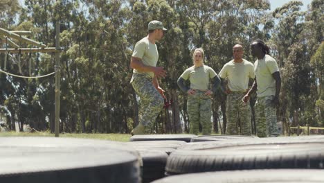 diverse group of soldiers listening to male instructor explain exercise on army obstacle course