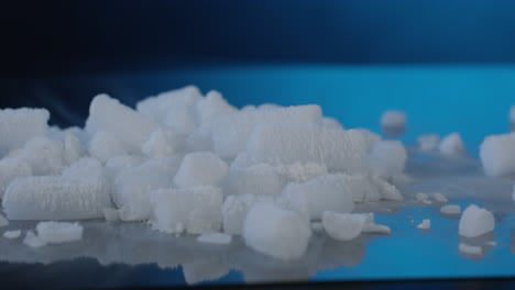 dry ice pellets on glass in front of dark blue background