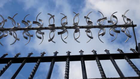 prison barbed wire steel gate looking up to blue cloudy sky dolly left