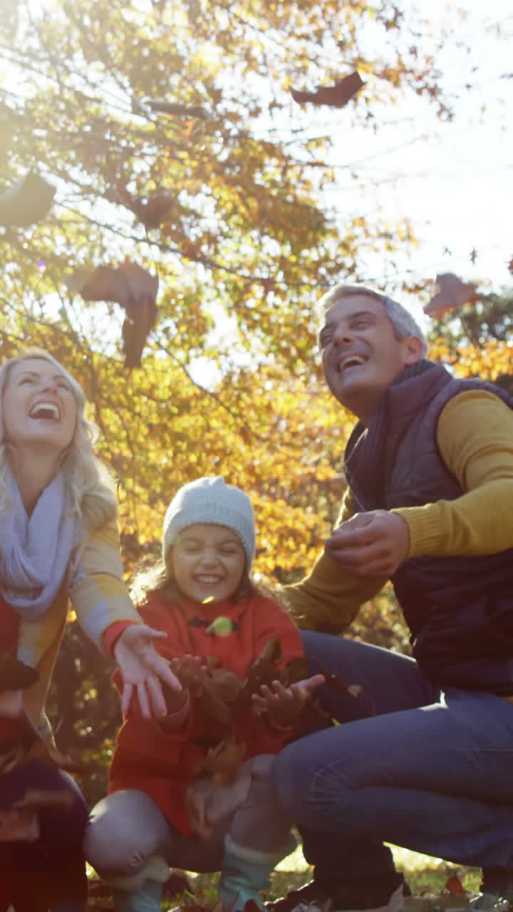madre padre e hija arrojando hojas al aire libre