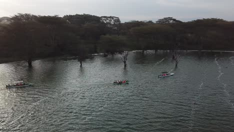 Vista-Orbital-De-Drones-De-Un-Crucero-Por-El-Río-Con-Un-Grupo-De-Personas-Navegando-En-El-Lago-Naivasha,-Kenia