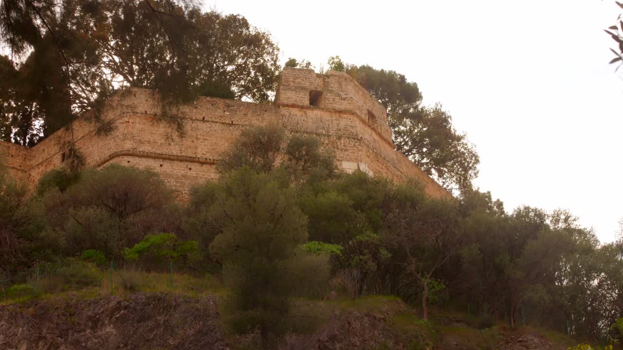 Exterior view of ancient Prince's Palace of Monaco fortress walls on slop hillside, Monaco