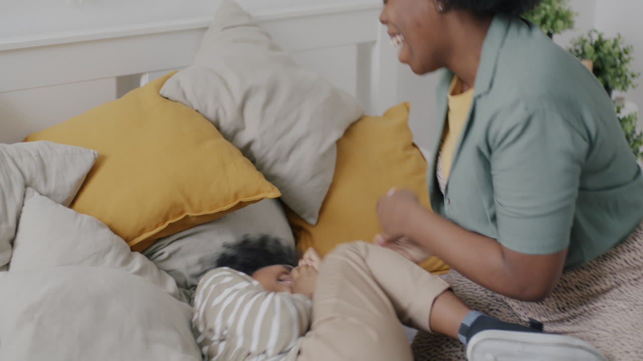 Mother and Daughter Playfully Tickling in Bed