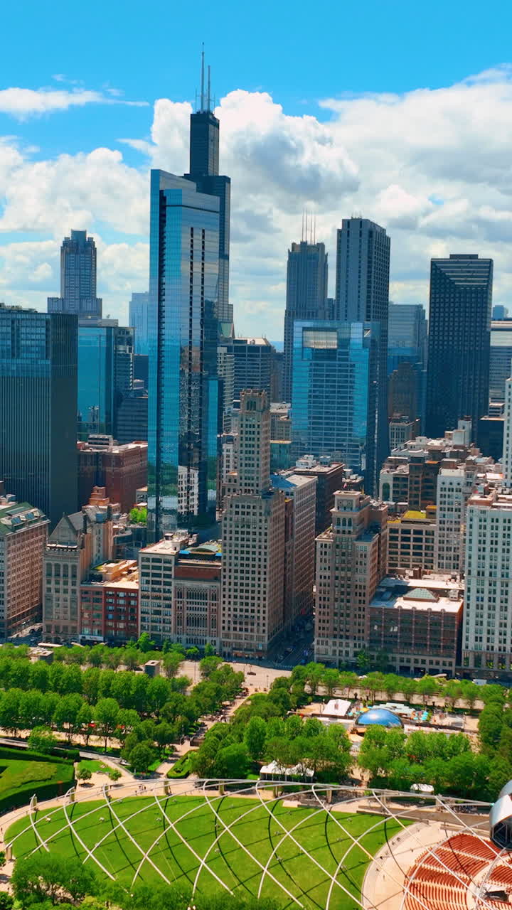 Aerial view of green parks and entertainment area in downtown Chicago. Tall famous skyscrapers against blue sky with clouds. Vertical video