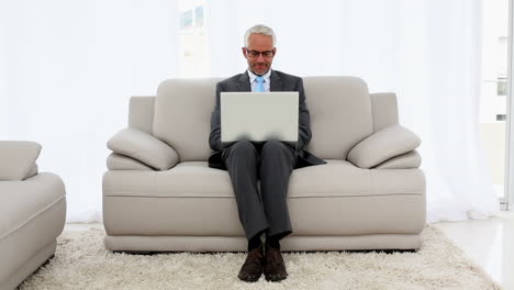 smiling businessman using laptop on the couch