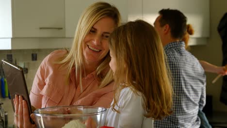 mother and daughter using digital tablet while preparing food 4k