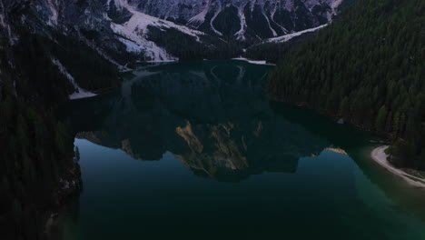 drone shot tilting over the mirroring lake pragser wildsee, in sunny dolomites, italy