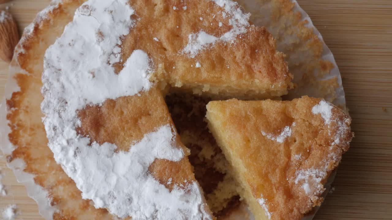 Tarta de Santiago with almonds on a wooden board, close-up view