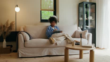 woman relaxing and using tablet on couch