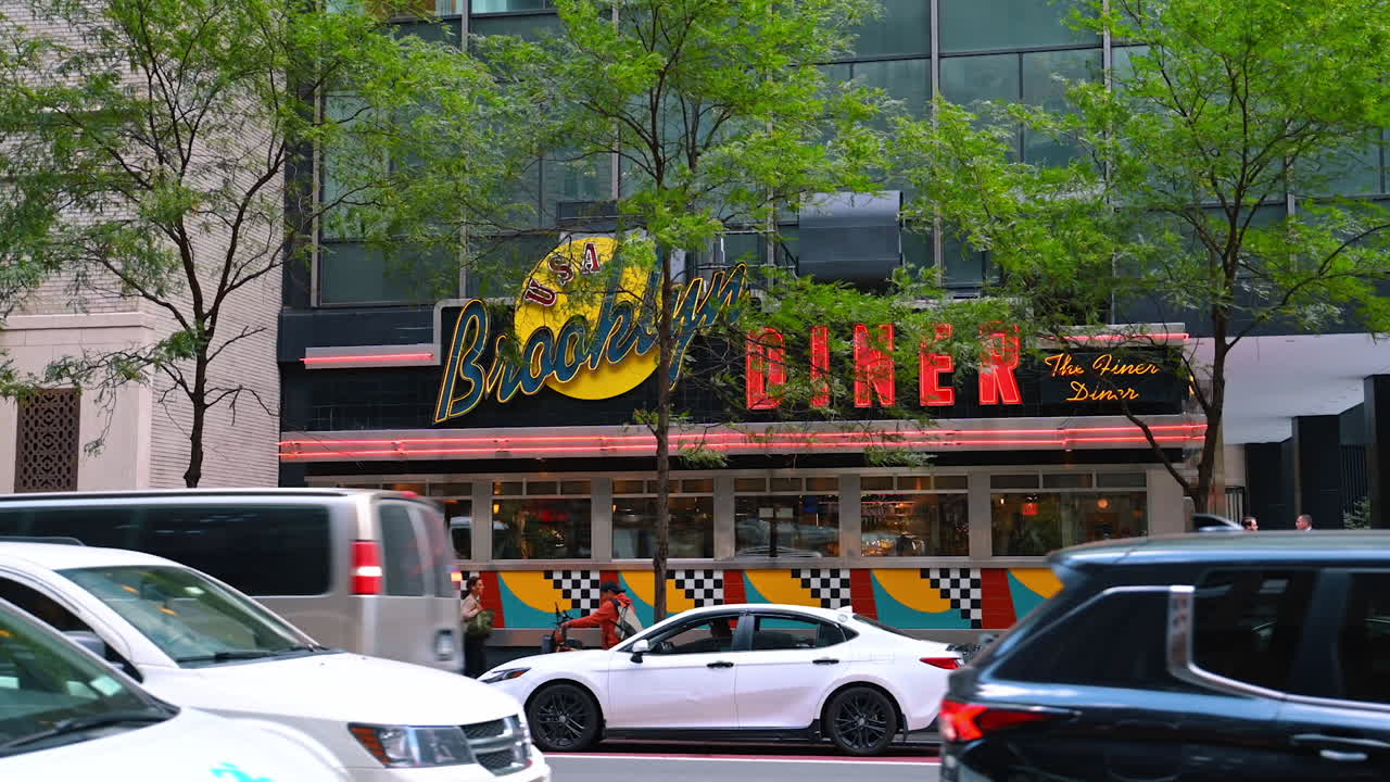 New York, USA, 1 August 2025: Colorful neon Brooklyn Diner sign with cars passing by in Manhattan