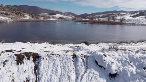 aerial over mountain frozen lake with snow ice sunny day blue sky