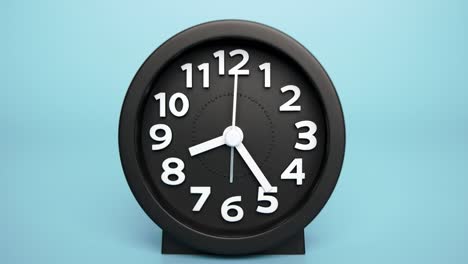 black alarm clock isolated on a blue background, time starts walking at 8 o'clock.