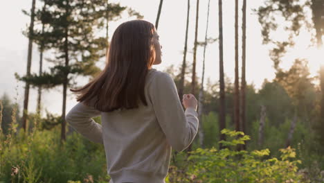 young woman athlete runs on forest glade at sunset. cardio workout of muscle building with views of sunlight and trees in wild. countryside and fitness alone