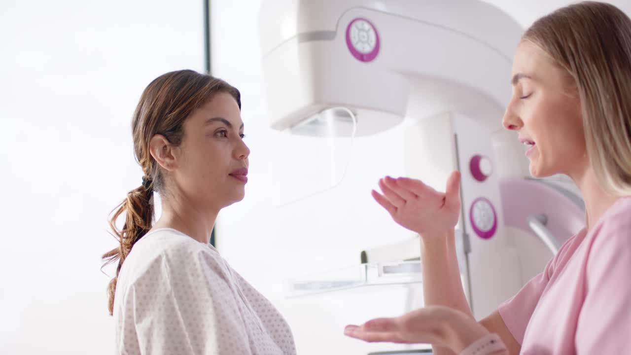 Before exam, woman patient standing while woman tech showing positioning adjusting unit, copy space