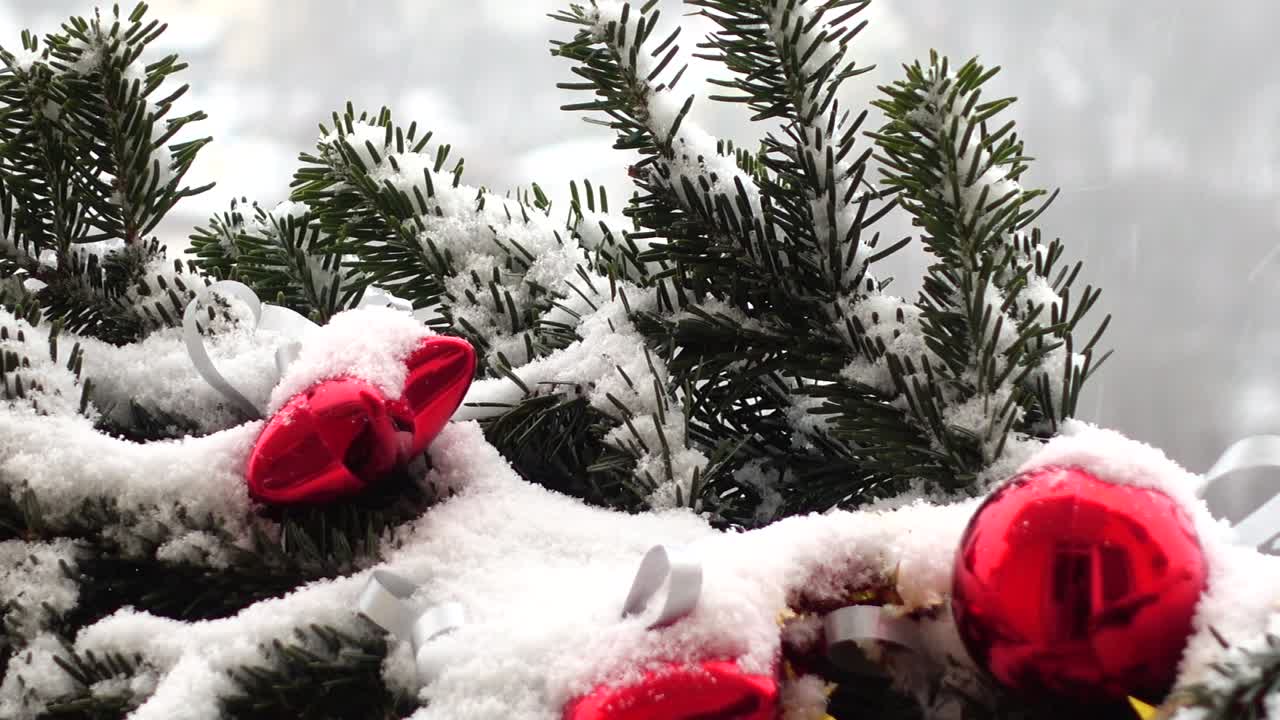 Kar altında oyuncaklarla süslenmiş yılbaşı ağacı dalları.