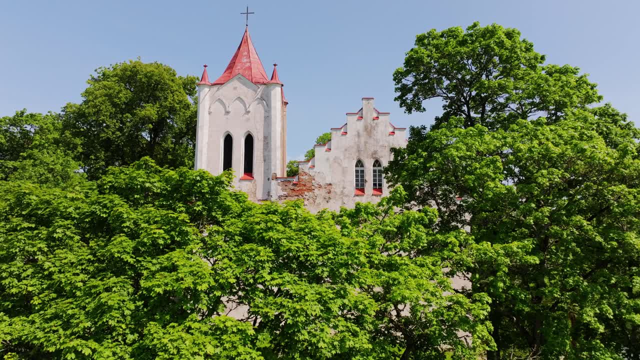 Establishing of old Aizpute Lutheran church tower framed by lush spring greenery