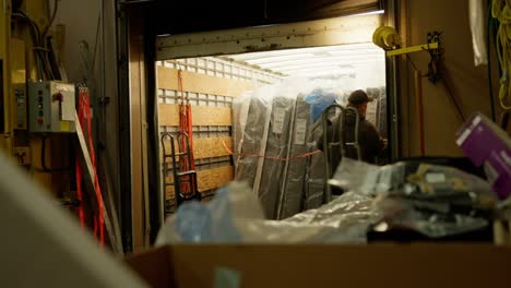 a male warehouse employee loads mattresses into a delivery truck
