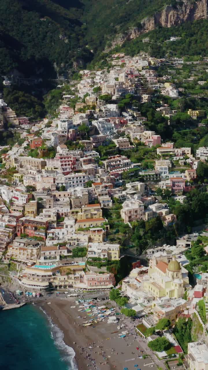 Vista aerea verticale dall'alto del famoso villaggio di Positano nella Costiera Amalfitana. La destinazione di viaggio più popolare in Italia con case colorate sulla scogliera che si affacciano sulla spiaggia e una barca ormeggiata.