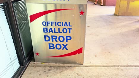 people walk by official ballot drop box for voting in american democratic election by mail