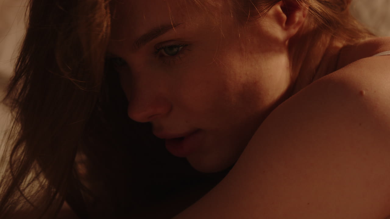 Stunning portrait of an attractive woman raising her head and long hair in slow motion while posing in bed