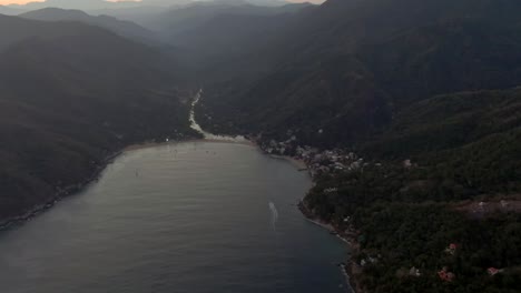 idyllic seascape revealed dense tropical mountains on yelapa town during misty morning in jalisco, mexico. aerial tilt-up
