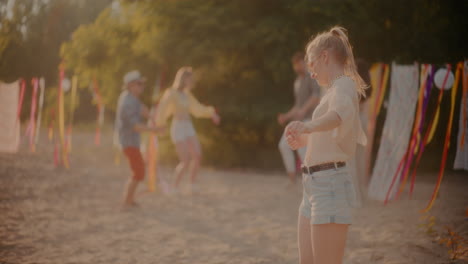 Fröhliche-Blonde-Frau-Tanzt-Am-Strand