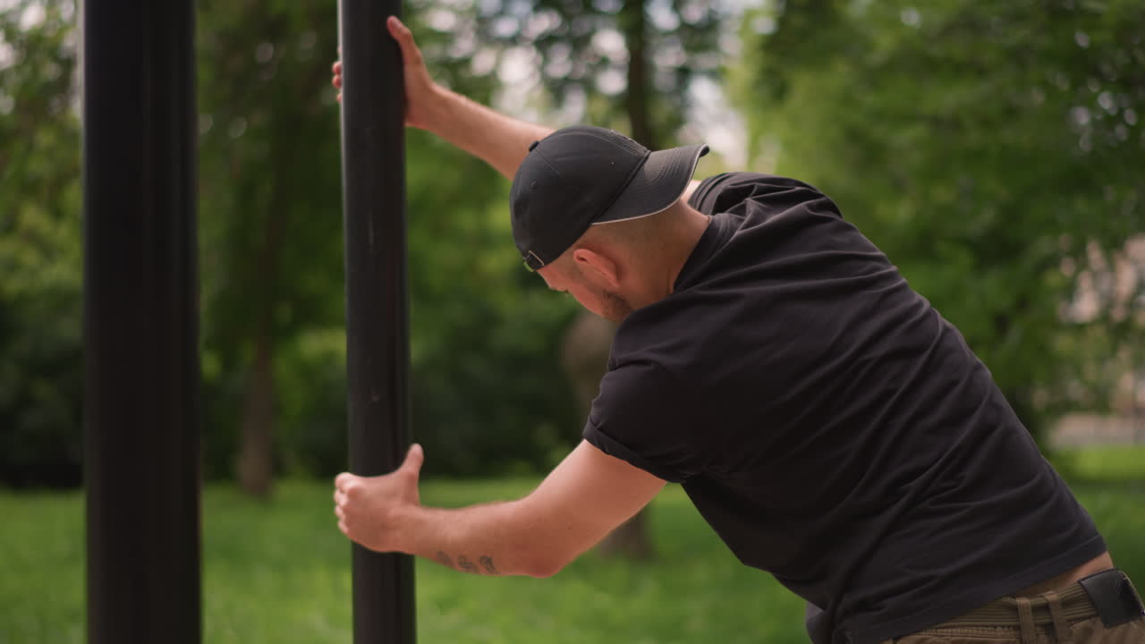 Person Sets Up For Workout Outside, Man Arranges Fitness Equipment For Calisthenics Warmup Session, Individual Is Adjusting Outdoor Exercise Bar For Calisthenics And Strength Training Routine