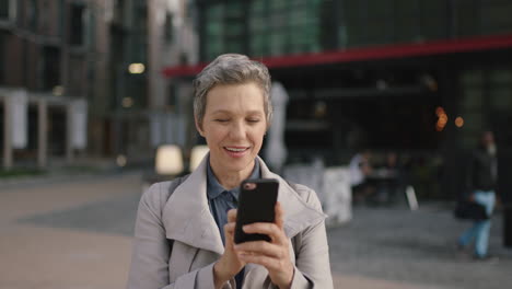 portrait of mature professional business woman waiting in city enjoying texting browsing using smarphone mobile technology in city