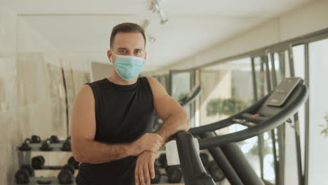 young strong athlete male man with face mask posing, looking to camera in the gym. close-up.