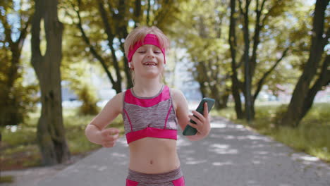 athletic fitness sport runner child girl walking, using smartphone listening music with earphones