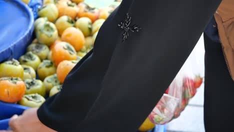 mujer comprando fresas y persimones en un mercado