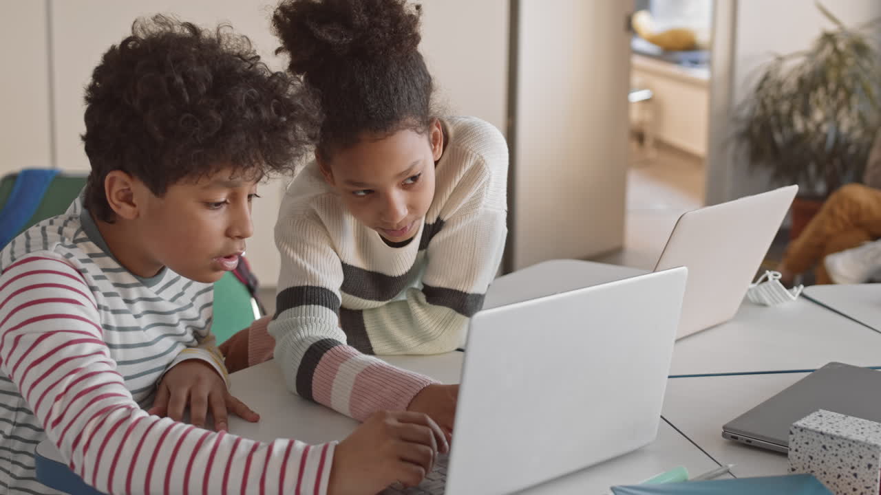 Afro-American Siblings Playing on Laptop in Classroom