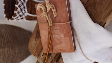 vertical boho room decor - rustic leather journal on a wooden chair with dried sprouts, gimbal close-up dolly zoom