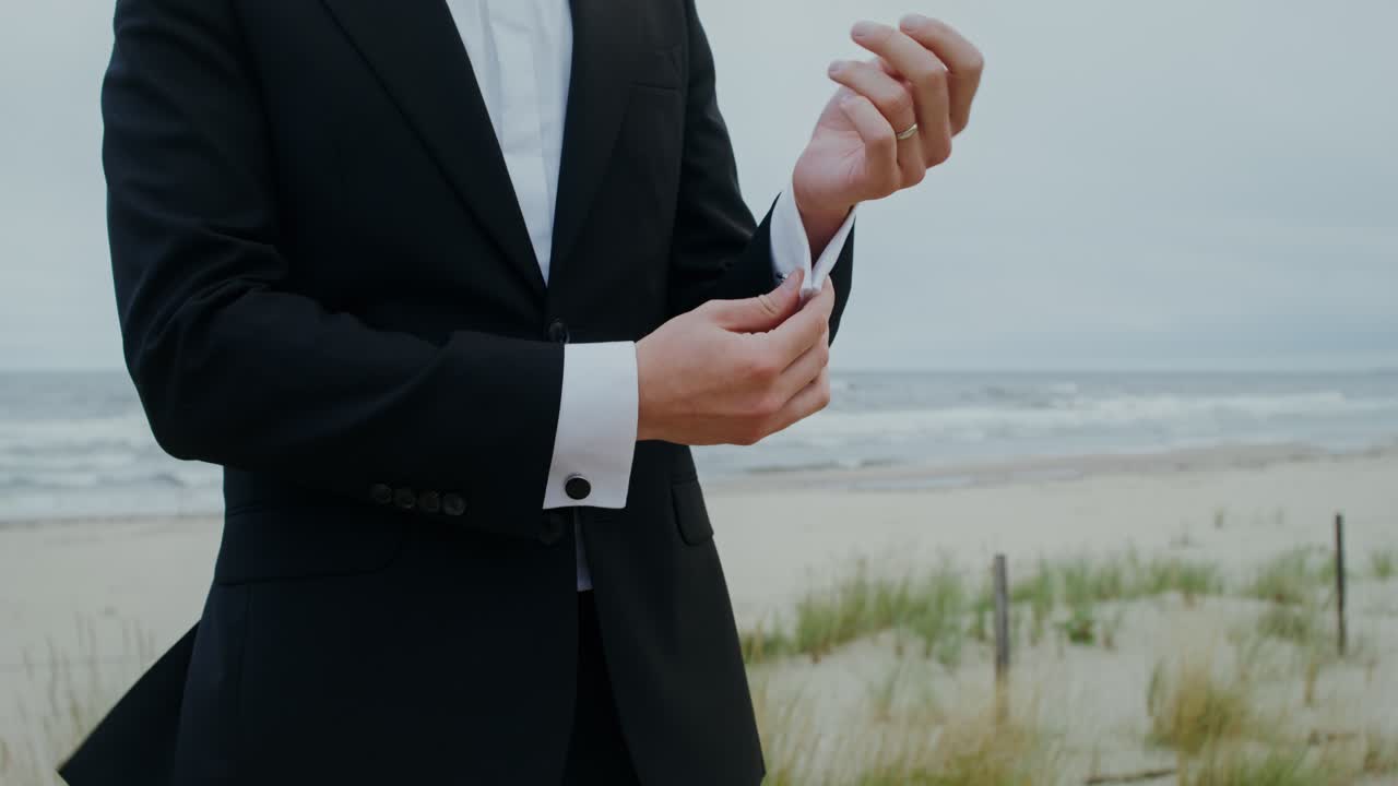 Groom Adjusting Cufflinks on Beach